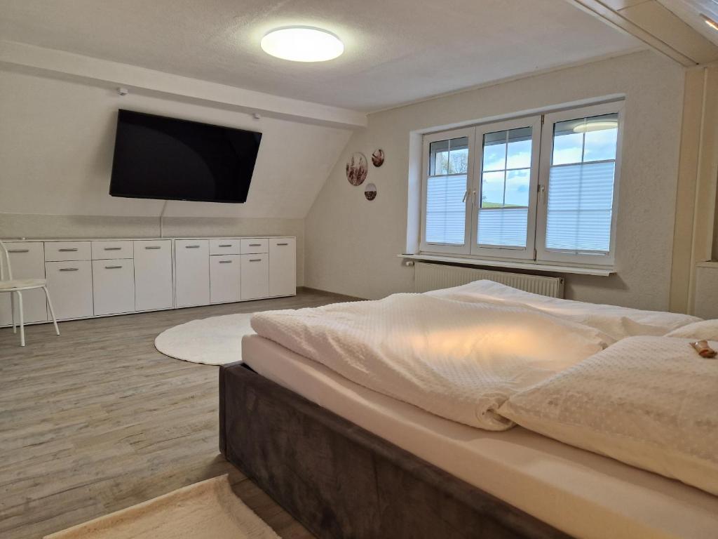 ein Schlafzimmer mit einem großen Bett und einem Flachbildfernseher in der Unterkunft Ferienhaus Hasenhügel mit Seeblick in Schwedt